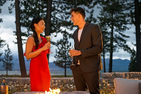 A young couple having cocktails outside next to a fire pit at the Lodge at Edgewood